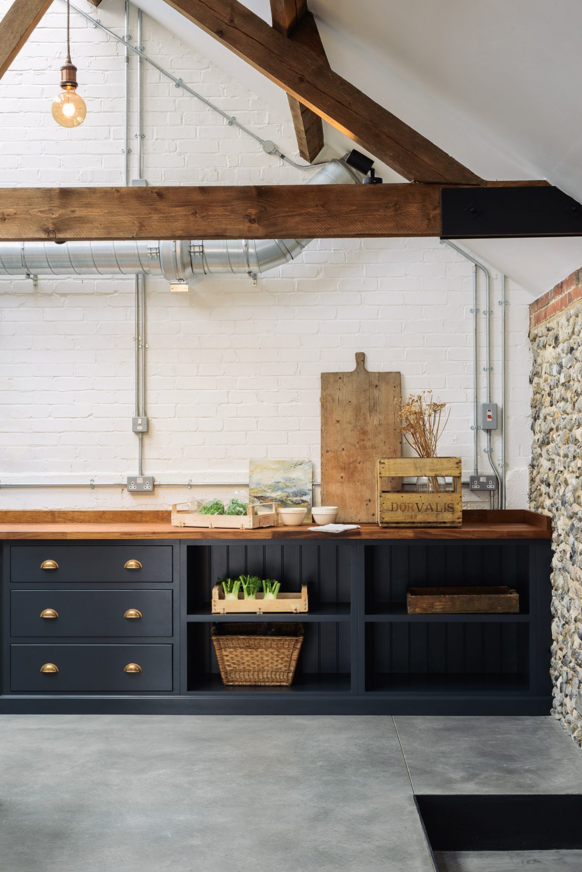 Polished concrete floors are beautifully softened by warm iroko worktops and original wooden beams. 