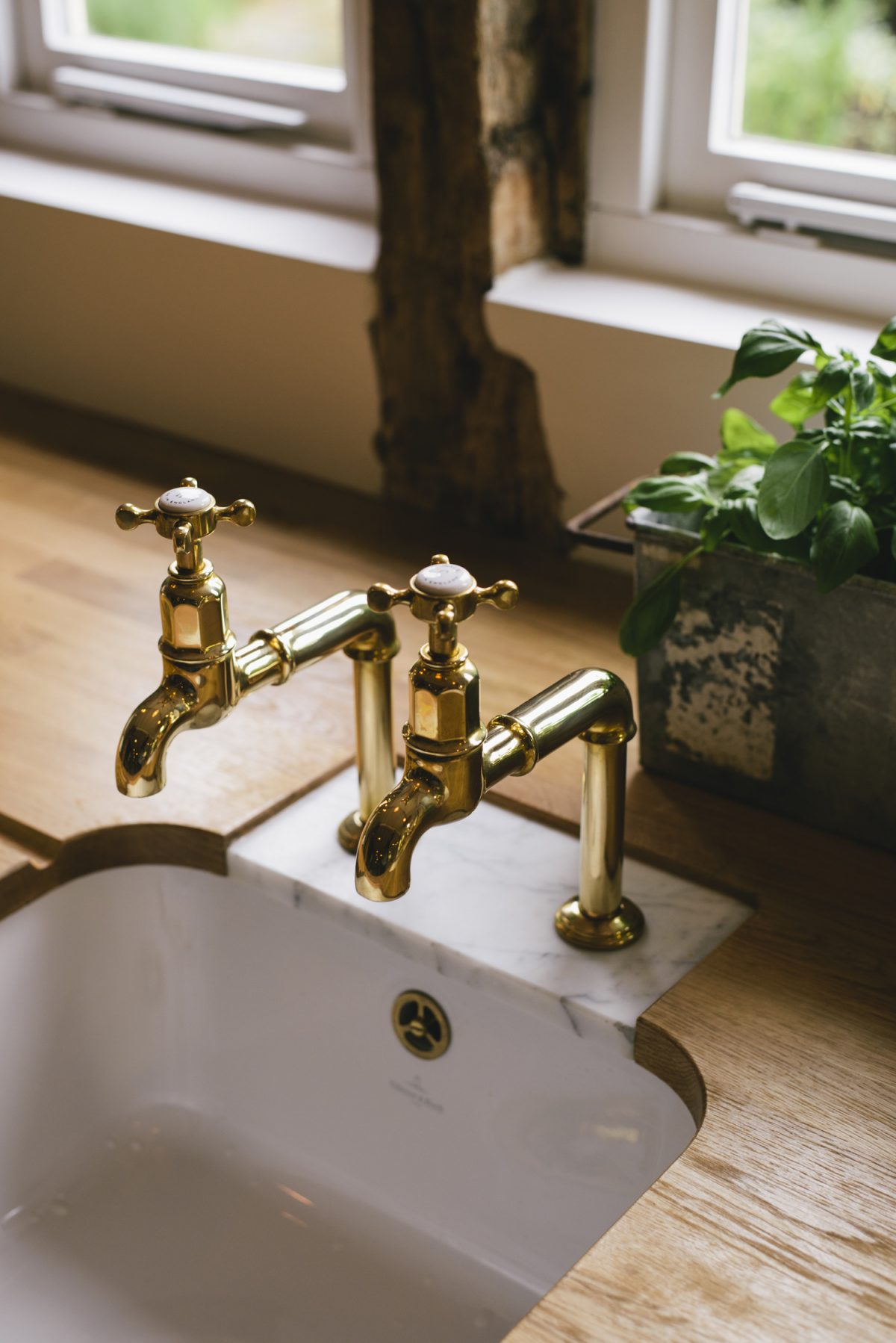 A pair of Aged Brass Mayan Taps set into a Carrara marble insert to prevent water damage.