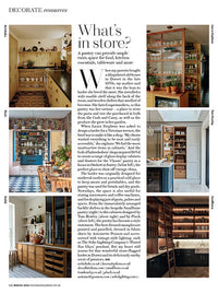A page of a magazine, in the centre is a column of black text and either side three small photos of kitchens run down either side of the page.