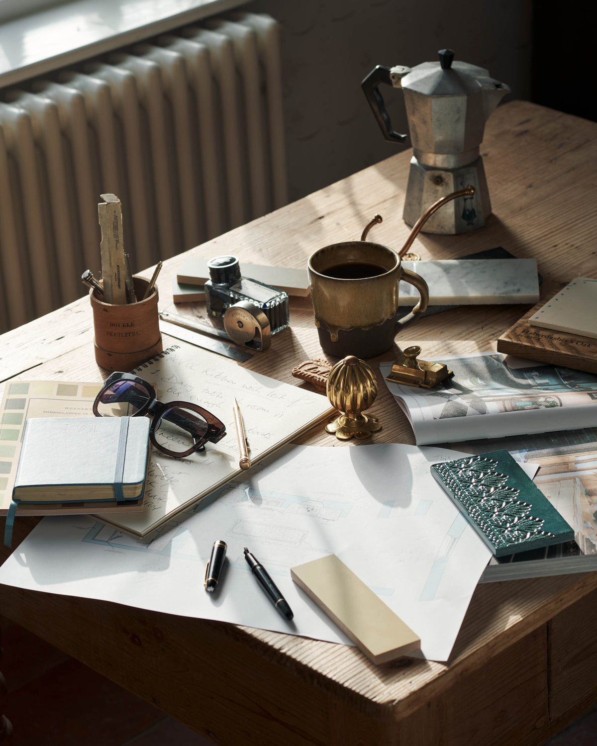 Wooden desk with coffee mug, notebook, and other items in a home office setting.