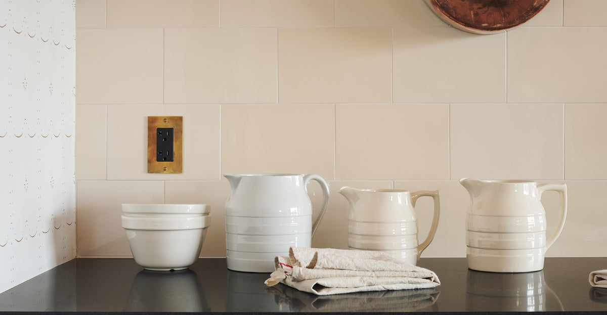 an image of the heirloom brass outlet as the main focus on a cream subway tiles with white tableware as decoration.