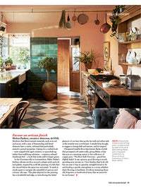 A page of a magazine, the top half is a photo of a kitchen with an eclectic vibe with pink walls, teal wall tiles, black and white floor tiles. The bottom section of the page is made up of two columns of black text.