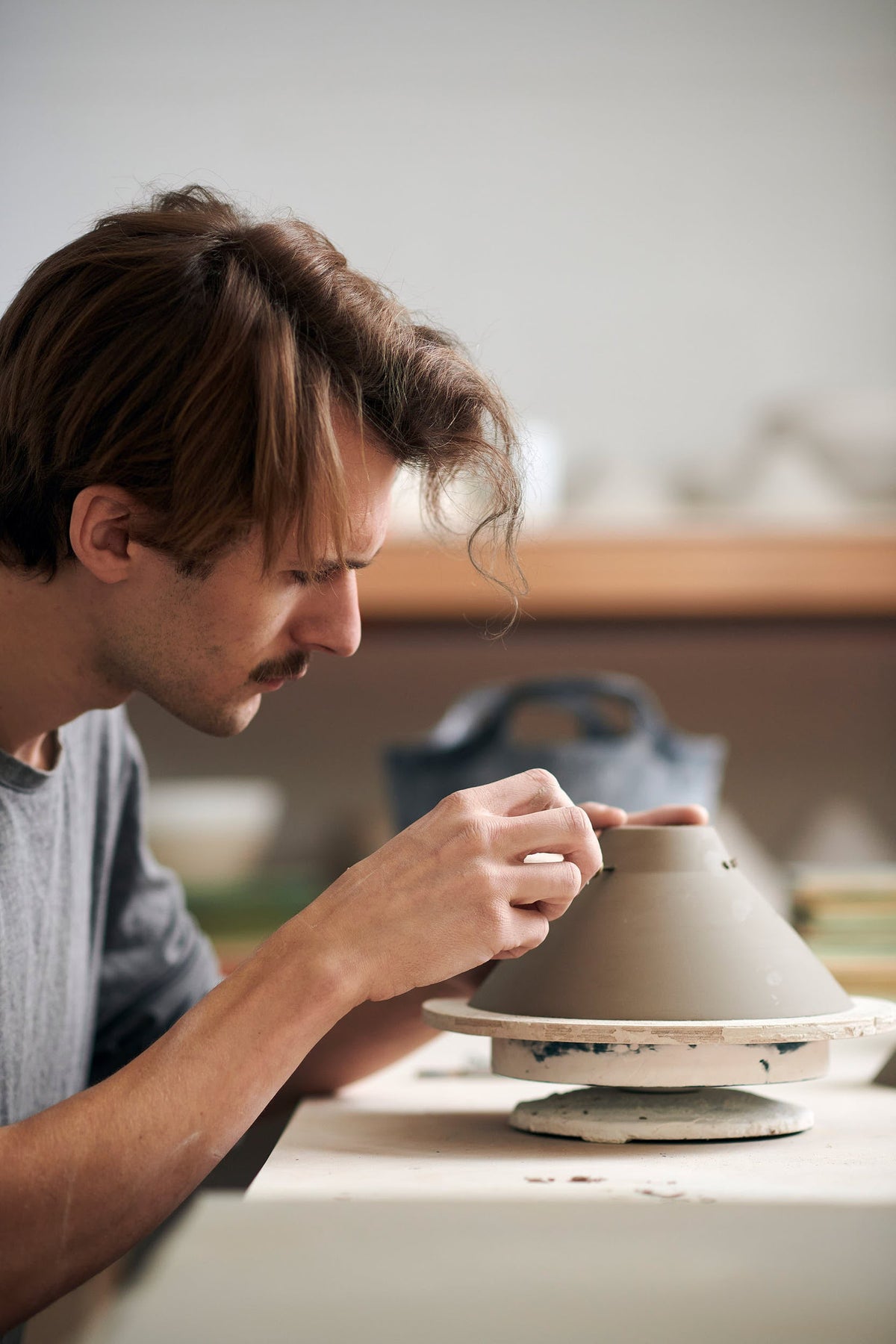 A ceramicist carefully poking air holes in the clay porcelain lamp piece.