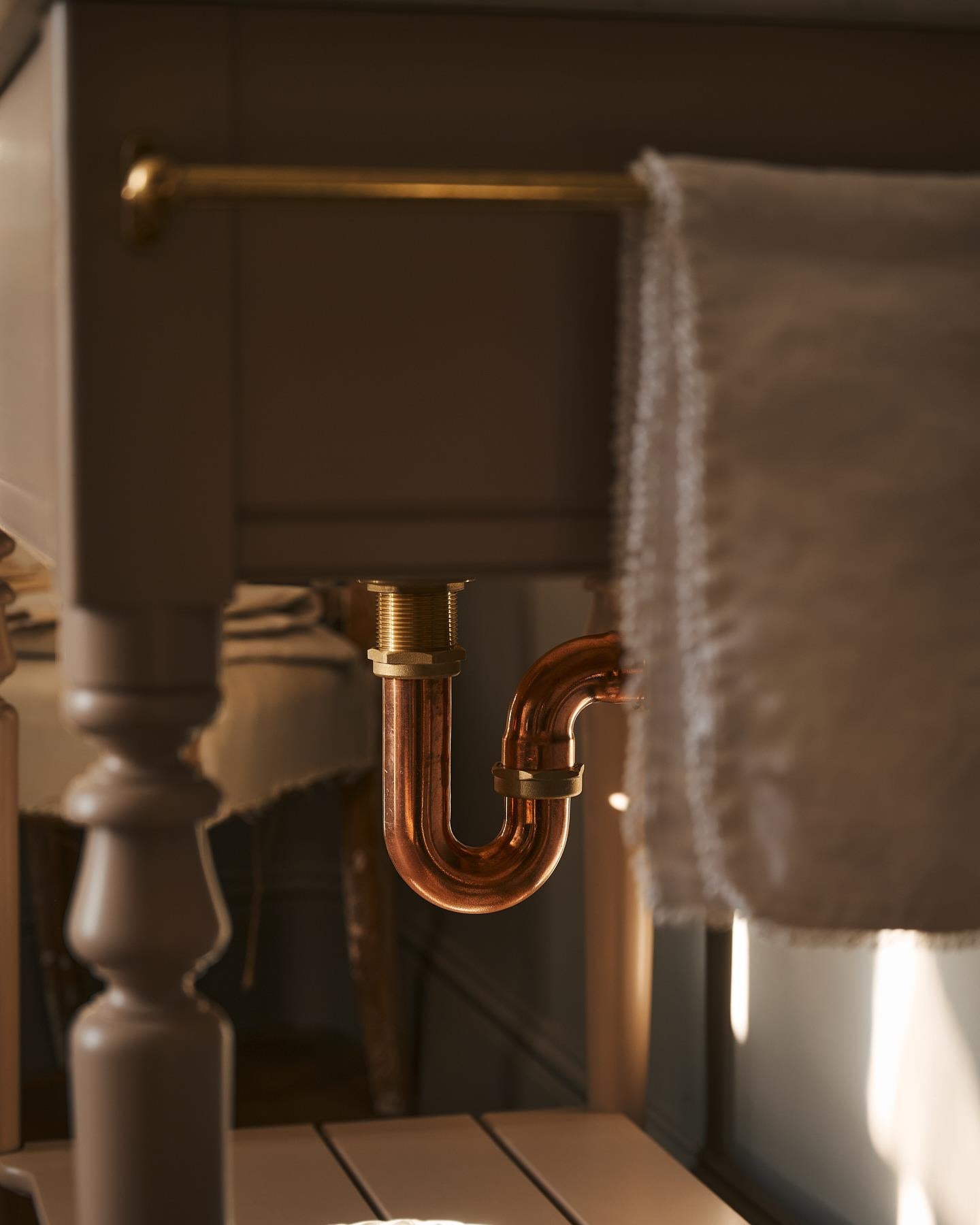 A copper p-trap fitted to a Victorian-inspired washstand.