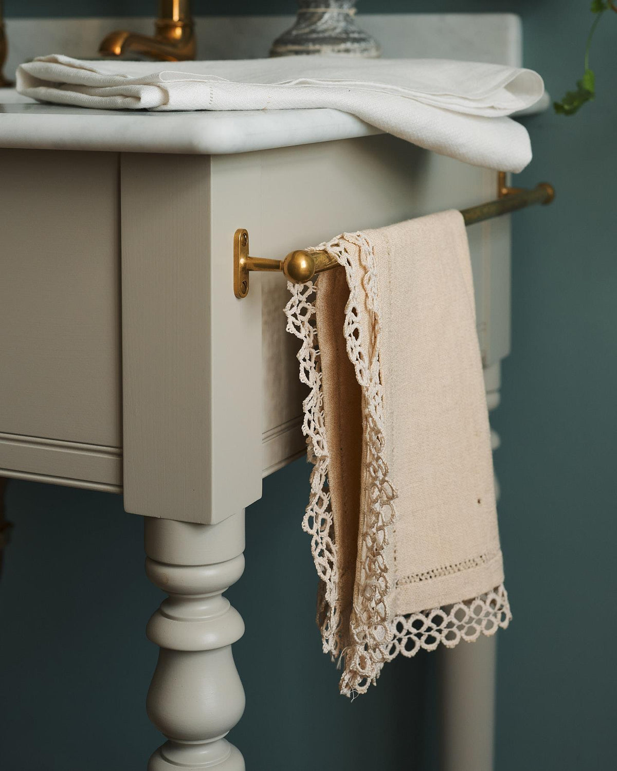 A detailed view of an aged brass towel rail attached to the right side of a Victorian-inspired washstand, a vintage lace hand towel hangs from the rail. | Right Towel Rail shown TEST