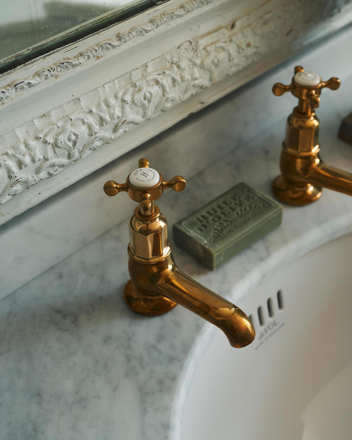 A close-up oblique view of an aged brass pillar taps for a bathroom basin sink. TEST