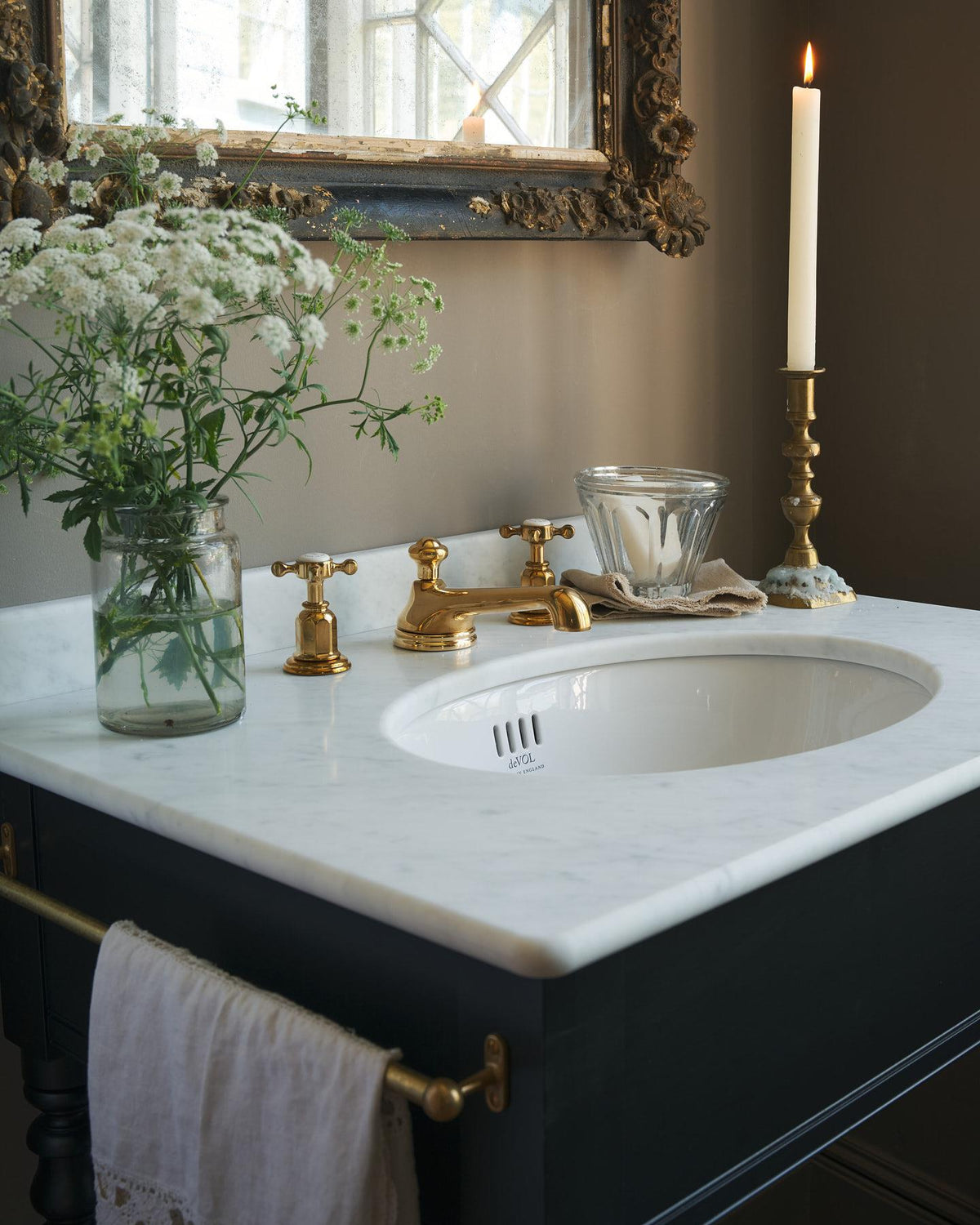 An oblique view of an aged brass mixer tap for a bathroom basin sink fitted to a black painted washstand. TEST