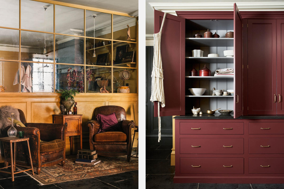 A busy and vibrant Refectory Red Shaker kitchen features a closed larder with drawers and a Belgian blue limestone worktop. Adorned with vintage furniture, old books, rugs, artisan ceramics, and tea towels, creates a bright and wonderfully social kitchen space.
