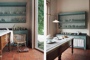 An internal image of the Heirloom Collection display in deVOL's LA showroom. Walls are covered in the Ditsy Delft wallpaper, an Heirloom Dairy table, and the kitchen cupboards are painted in Trinity Blue with contrasting dark worktops and a rich and earthy terracotta square floor.