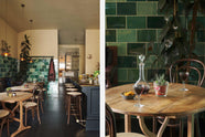 A chic and glamorous Bobbin Black Haberdasher’s bar featuring a kitchen island with a polished brass worktop, a brass foot rail, vineyard tables, bentwood café chairs, woven top bentwood café stools, petite amber frilly glass pendant lights, and a large display of Emerald green London splashback tiles. Adorned with wine glasses, plants, crystal handle holders, trays, and vintage decanters, it creates a beautiful and intimate personal bar.