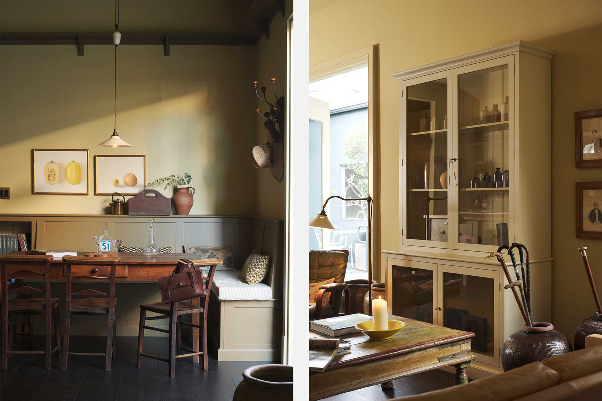 A simple buttery yellow Shaker living space features a Folgate green bespoke bench seat with an open base cabinet, a shelf, a rise and fall pendant light, a curiosity cupboard, and a cohesive set of vintage table and chairs. Lovingly adorned with artisan ceramics, paintings, books, a coat rack and cushions, creating a cosy and Mediterranean cafe-inspired social space.