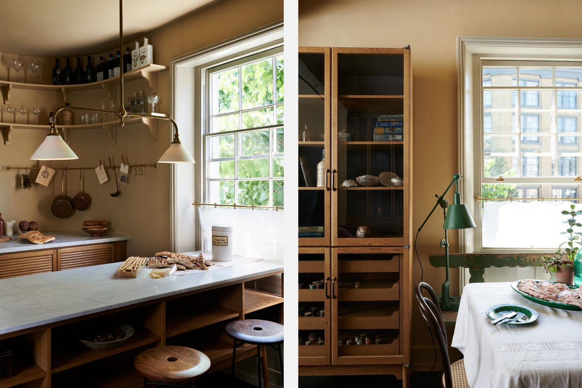 A cosy and sophisticated Haberdasher’s kitchen features a cooker run with a Carrara marble worktop, a small prep table, bespoke curved shelves, and muted yellow walls. Beautifully decorated with Creedy stools, a deVOL Heirloom gaselier light, Heirloom wall lights, aged brass hanging rails, copper pans, focaccia bread, vintage items, and artisan ceramics, this kitchen creates a bright and warm space.