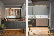 A chic and simple Sebastian Cox basement kitchen features a long sink run with two sets of copper sinks, aged brass Mayan taps, a Carrara marble worktop, glazed wall cupboards, a large kitchen island with a gas cooker, a copper worktop, and a breakfast nook. This kitchen creates a cool and atmospheric space, beautifully decorated with luscious green house plants, vintage items, drinking glasses, a plumber’s stool, and a simple pendant light.