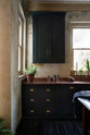 A closer look at an elegant classic kitchen’s sink run reveals an aged copper worktop, wall cupboards, and a marble worktop heirloom dairy table. The pantry-blue wall cupboard takes centre stage, providing functional storage even in the corner of the tall-ceilinged kitchen.