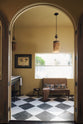 A beautiful butter-yellow powder room, you’ll find a collection of antique furniture, books, magazines, a lace throw, pillows, and a Parisian chequered marble floor.
