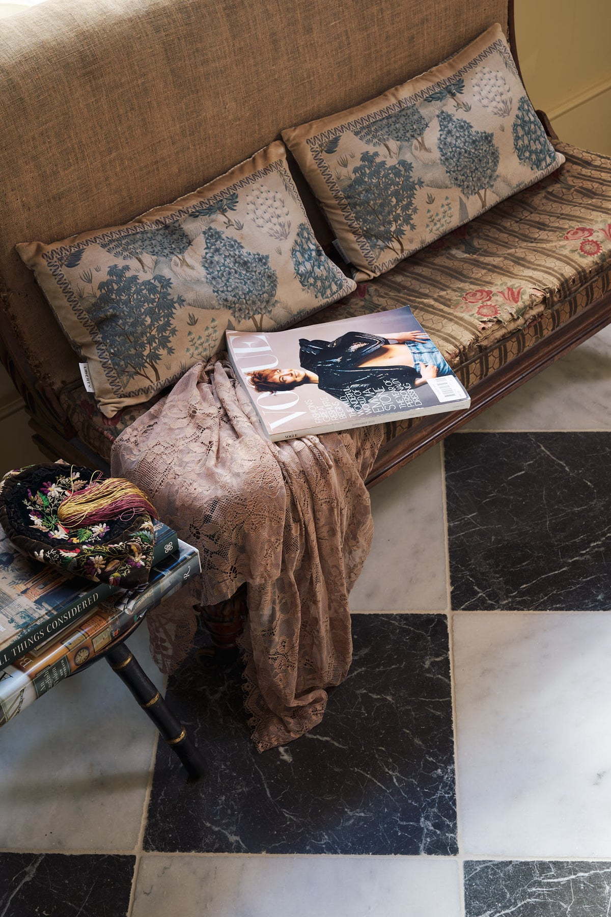A beautiful butter-yellow powder room, you’ll find a pair of Habedasher’s glazed base cabinets with ruched curtains, a collection of antique furniture, vintage paintings, and a Parisian chequered marble floor. Paired with floral wall candle holders and an old dress form, the room exudes a glamorous, vintage charm.