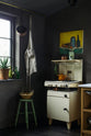 A quiet corner of a warm and inviting Haberdasher’s kitchen features a long sink run with a Carrara marble worktop. Adorned with a luscious green potted plant, vintage items, an orange teapot, a still art painting, and a beloved white gas stove, this kitchen creates a lovely exhibitionist space that is both beautiful and practical.