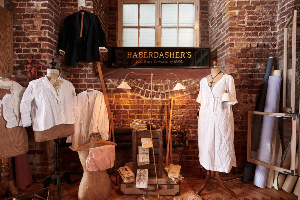 A closer look at the Grand Tour library lamp and the plug-in porcelain beaker lamp as part of the handsome range of oak furniture and lighting from the deVOL Haberdasher’s collection. Adorned with vintage furniture and items, dressmaker mannequins, and 1900s tailor tools, this space creates a beautiful homage to the English gentlemen’s haberdashery inspiration in a bricked wall showroom.