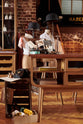A closer look at a handsome range of oak furniture and lighting from the deVOL Haberdasher’s collection features a kitchen island, and countertop cupboards. Adorned with deVOL Heirloom accessories, Helen stools, vintage furniture and items, dressmaker mannequins, and 1900s tailor tools, this space creates a beautiful homage to the English gentlemen’s haberdashery inspiration in a bricked wall showroom.