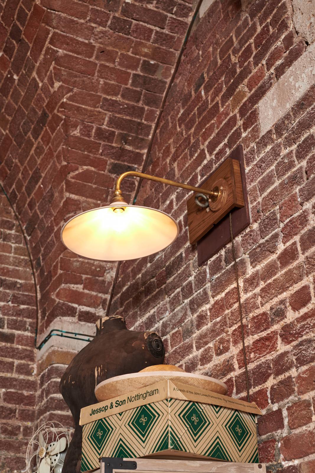 A closer look at the milk glass task light reveals its charm as part of the handsome range of oak furniture and lighting from the deVOL Haberdasher’s collection. Adorned with vintage furniture and items, as well as dressmaker mannequins, this space creates a beautiful homage to the English gentlemen’s haberdashery inspiration in a bricked wall showroom.