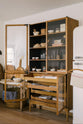 A closer look at a warm and spacious Haberdasher’s kitchen featuring a freestanding pantry with glazed doors. Adorned with vintage furniture and items, artisan ceramics, wicker baskets, tea towels, large wooden tapas boards, and wooden letterpress, this kitchen creates a contemporary yet nostalgic space.
