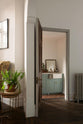 A top angled view of a beautifully detailed alcove features a Trinity Blue shaker kitchen with an L-shaped cooker and sink run. The kitchen includes a countertop cupboard topped with Carrara marble and a freestanding prep table in linen white with a copper worktop. The setting is in a well-preserved house with its original floorboards.