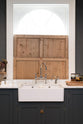 A charcoal-black, classic shaker kitchen features a U-shaped sink and cooker run with Carrara marble worktop, a double Belfast sink, and a chrome Ionian tap. Beautifully decorated with jars of different pickles, a vase of flowers, plastic cups, and the original Georgian wooden sliders, the family kitchen strikes a wonderful balance between modern style and timeless character.