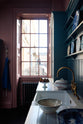 Looking across the sink run and through the adjacent sash window, a glimpse of Bath’s classic Georgian architecture unfolds outside. Light floods the room, casting a soft sheen on the painted teal cabinetry and Carrara marble worktop. The deep gold aged brass tap catches the light, adding dramatic warmth to the scene.