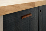 This is a closer look at a simple and contemporary Sebastian Cox kitchen’s long sink run, which has a solid oak worktop and an Inky Blue Black colour tint. Adorned with a warm copper bar and a copper ring pull, this kitchen creates a cosy space with industrial details and a practical finish.