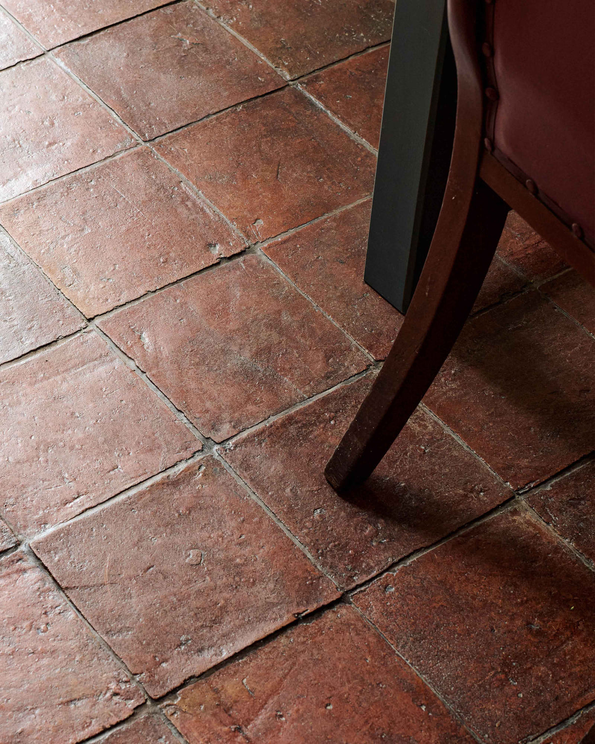 A close and oblique view of an antique beeswax treated terracotta square tiled floor.