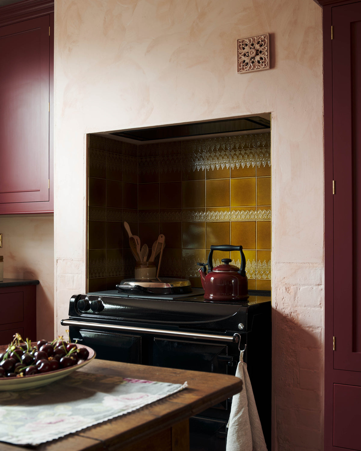 A display of Sepia Lace Market Tiles in a chimney breast alcove above a black range cooker.