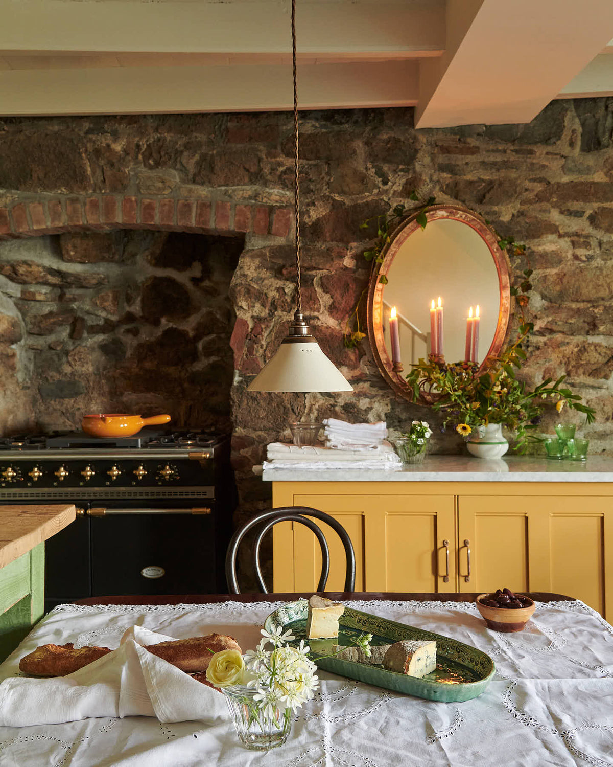 The quaint and glamorous cottage kitchen, in shades of green and scullery yellow, includes a marble-topped base cabinet. Lovingly decorated with vintage furniture, a sea green oval platter, wild flowers, and deVOL mini creamware lights, the space exudes personality and charm while respecting the cottage's original textures.