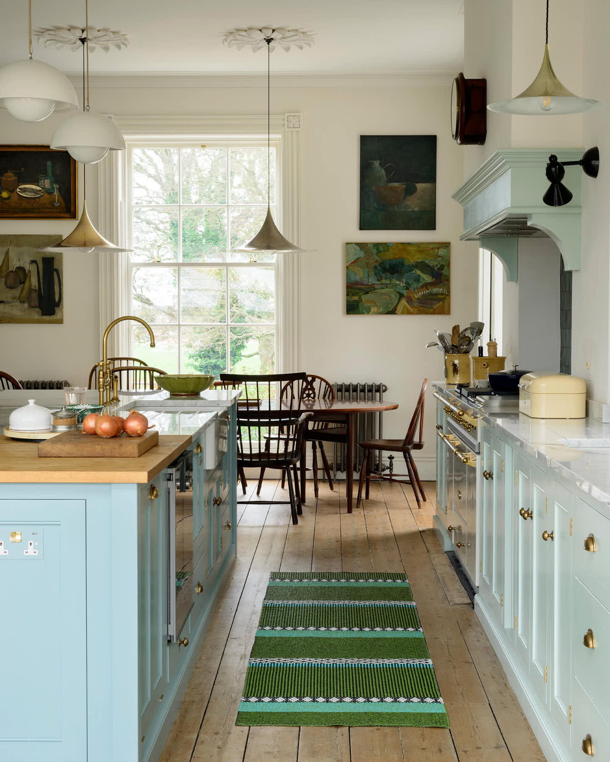 Nestled between a classic English kitchen featuring a cooker and sink run with a Carrara marble worktop, a suspended false chimney breast, a glazed wall cupboard, and a kitchen island with Carrara marble on one side and solid oak on the other, the cosy breakfast nook creates a seamless flow within the space.