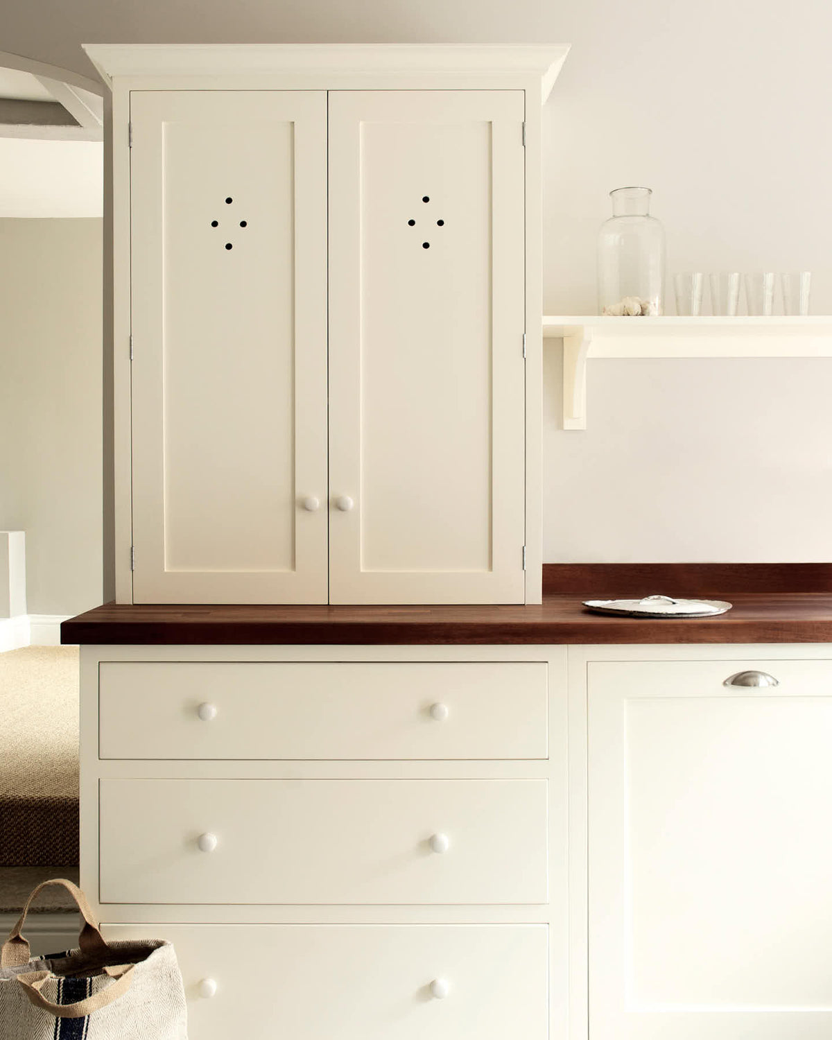 A minimalist white linen shaker kitchen featuring a dark polished sapele wood worktop with a countertop cupboard and an L-shaped sink run.