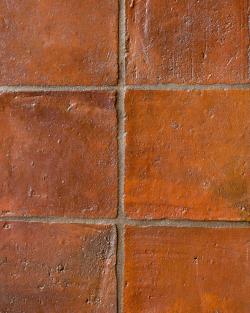 A close-up overhead view of square terracotta flooring with an authentic aged finish.