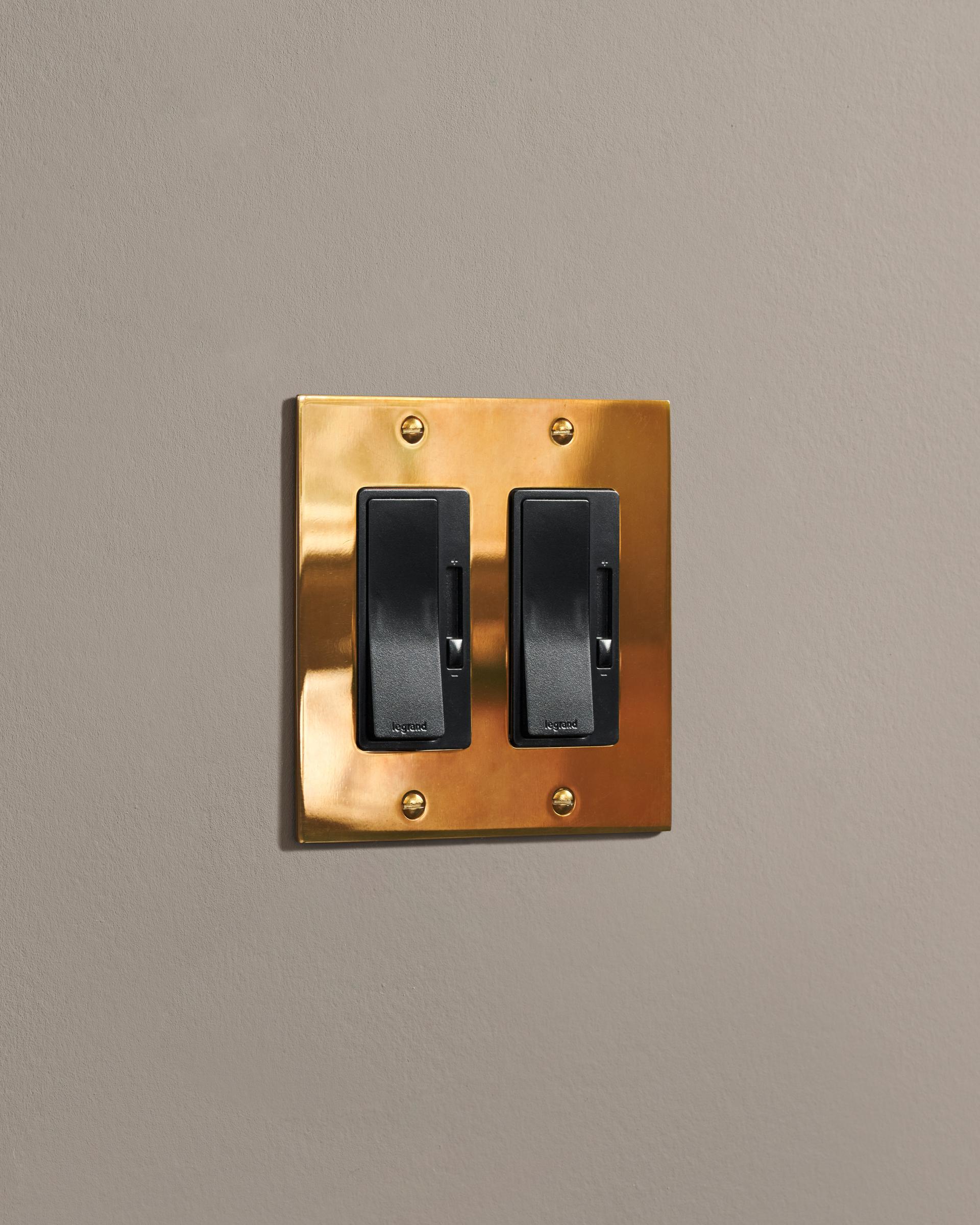 a side on shot of the rocker switch with slide dimmer on an heirloom brass plate.