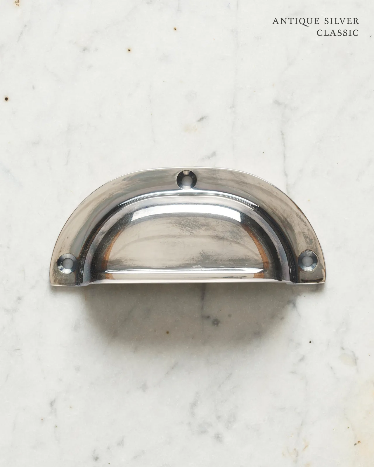 A classic cup handle for a kitchen cupboard or drawer with a tarnished silver finish.