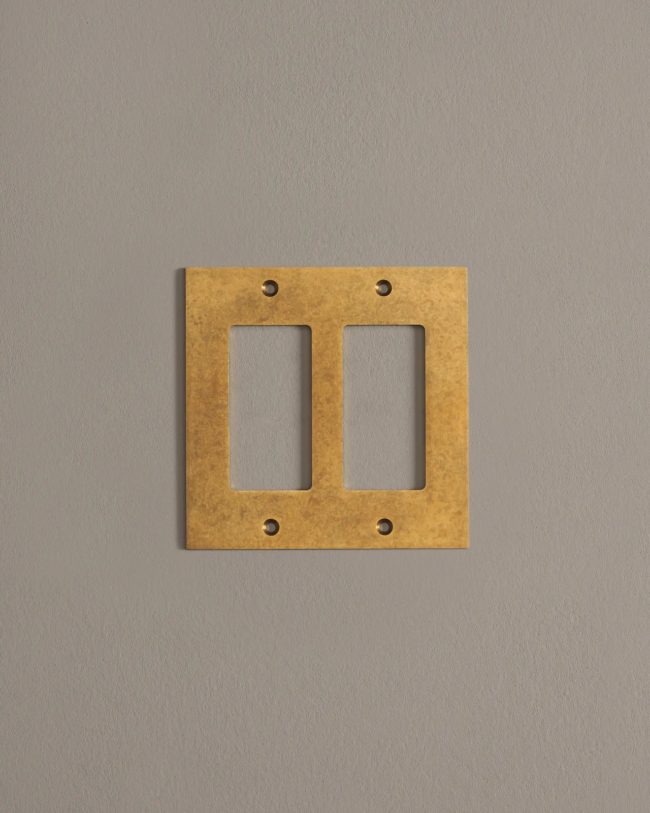 A straight-on view of a 2 gang cover plate in a warm burnished brass finish.