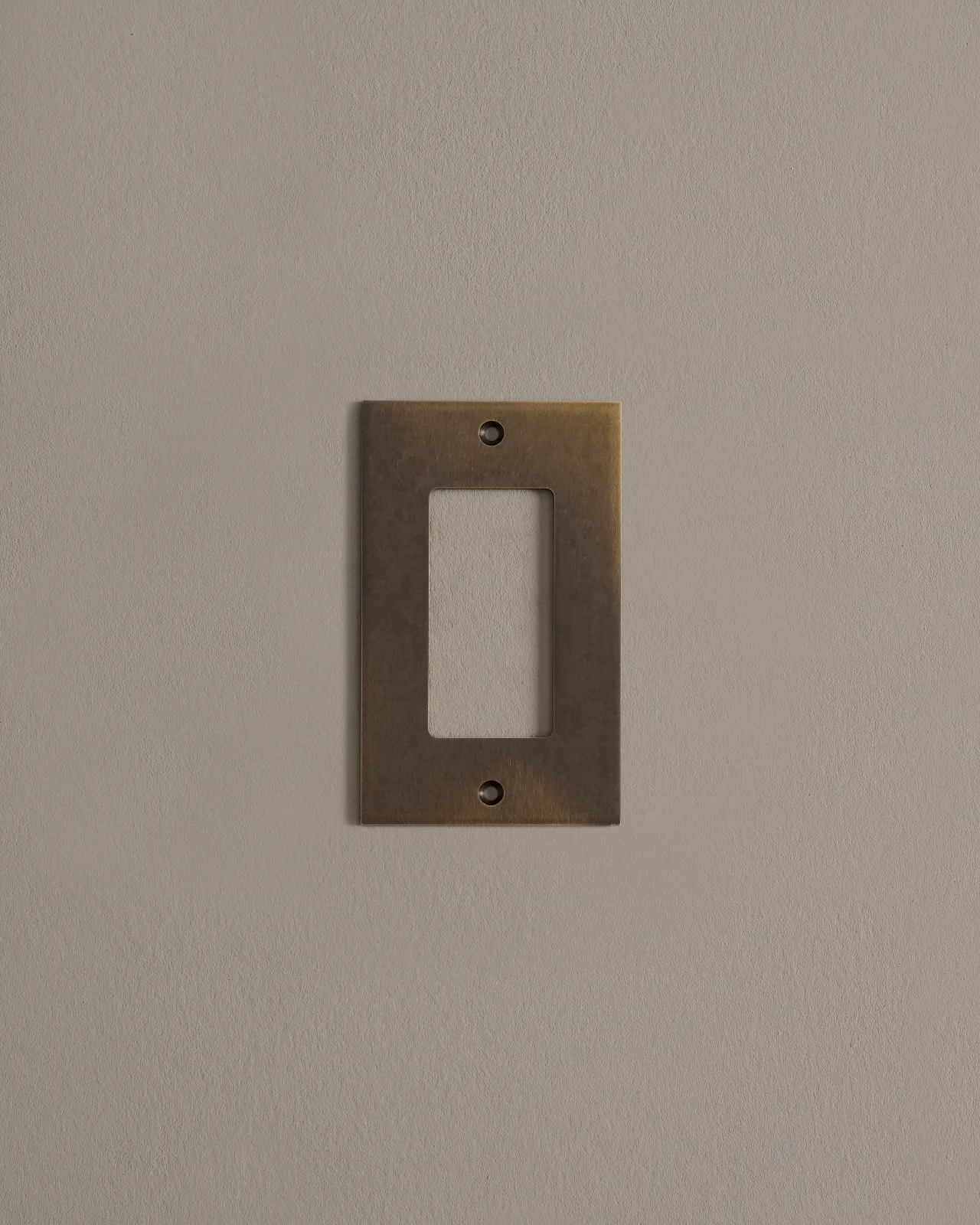 A straight-on view of a 1 gang cover plate in a dark burnished brass finish.