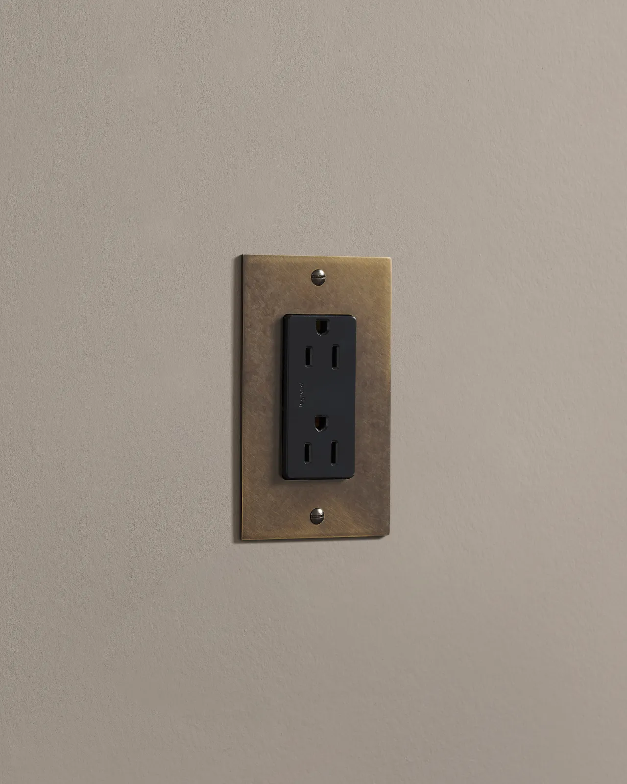A side-on view of a 1 gang cover plate in a dark burnished brass finish with a module.