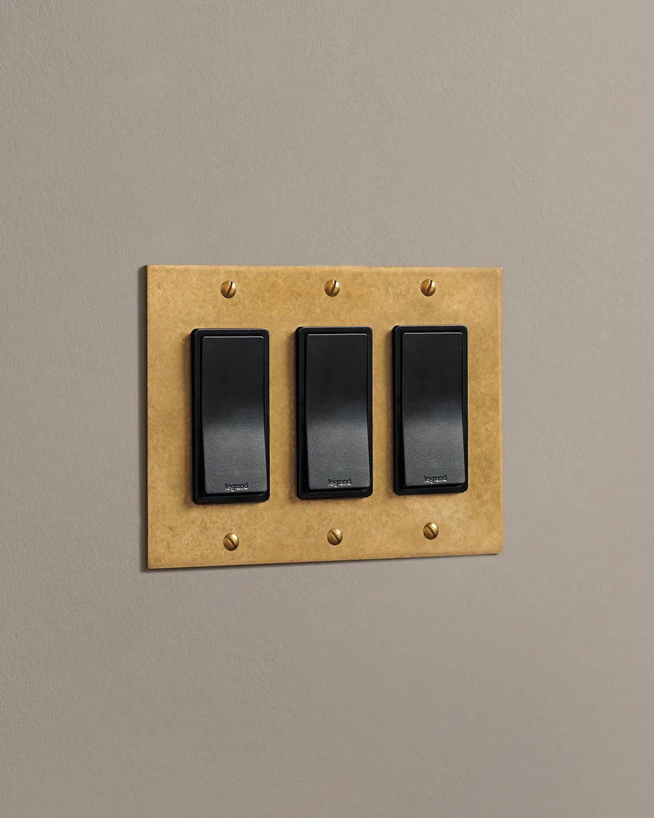 a side on shot of the rocker switch on an aged brass cover plate.