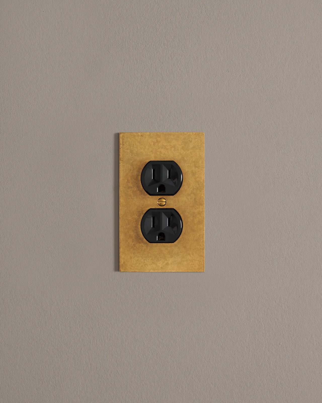 A front on shot on a duplex outlet on an aged brass cover plate.