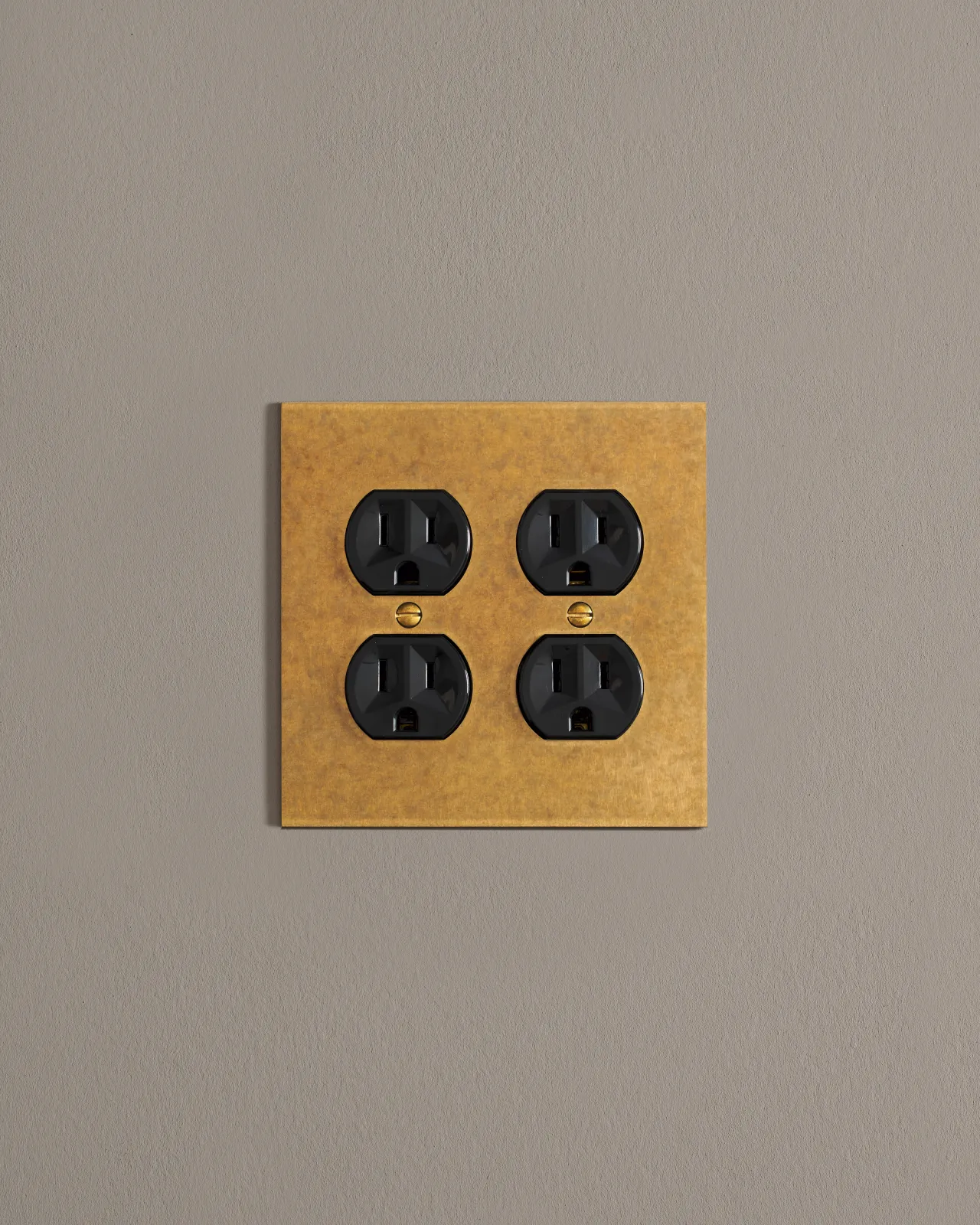 A front on shot on a duplex outlet on an aged brass cover plate.