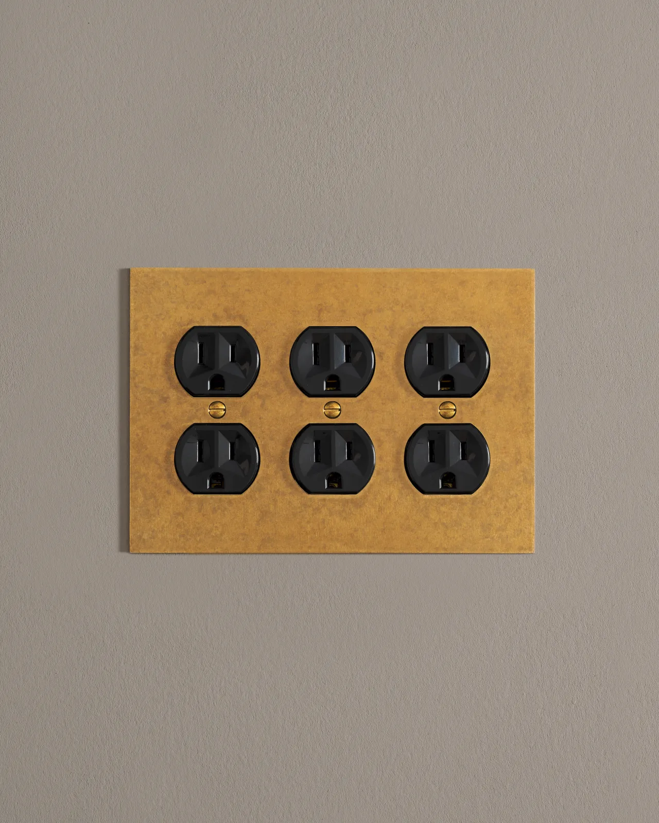 A front on shot on a duplex outlet on an aged brass cover plate.