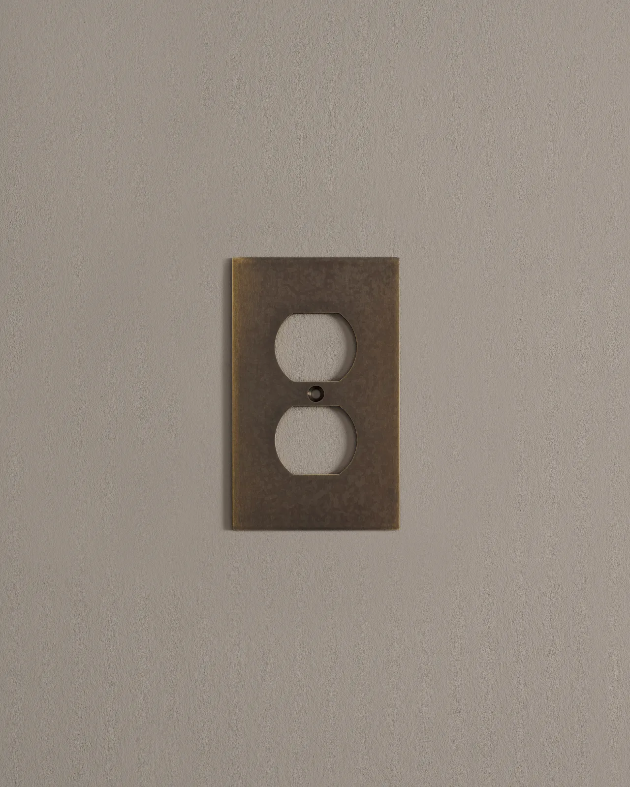 a front on shot of the duplex outlet cover plate in an oxidised brass finish.