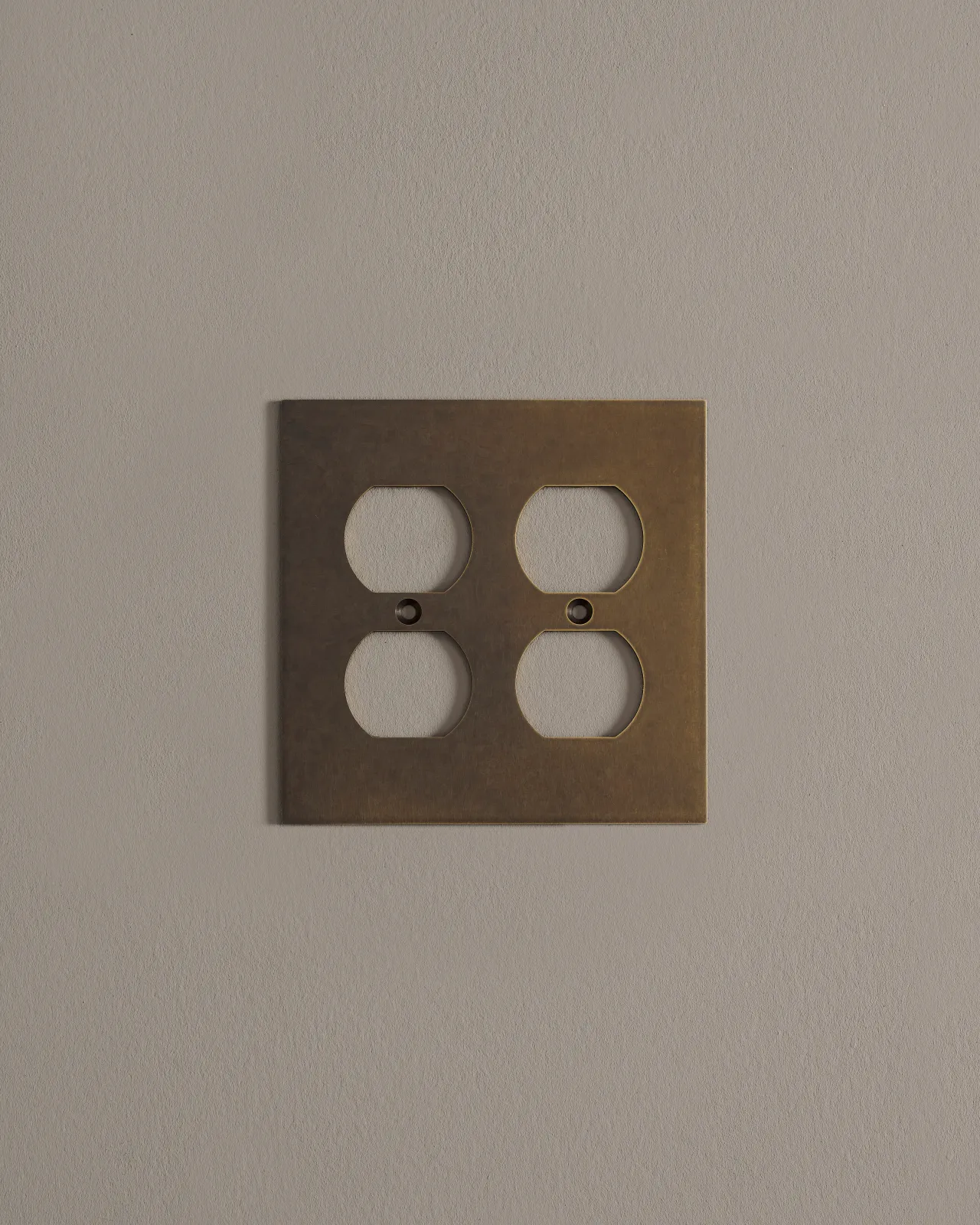 a front on shot of the duplex outlet cover plate in an oxidised brass finish.