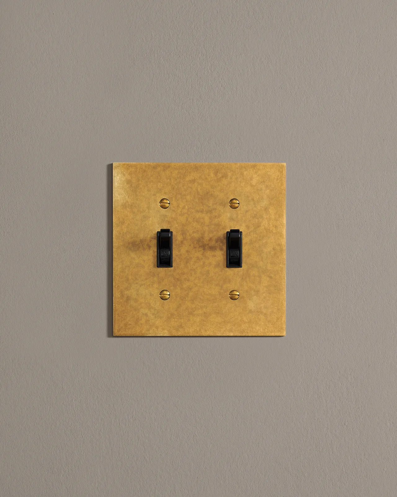 A front on shot on a toggle switch on an aged brass cover plate.