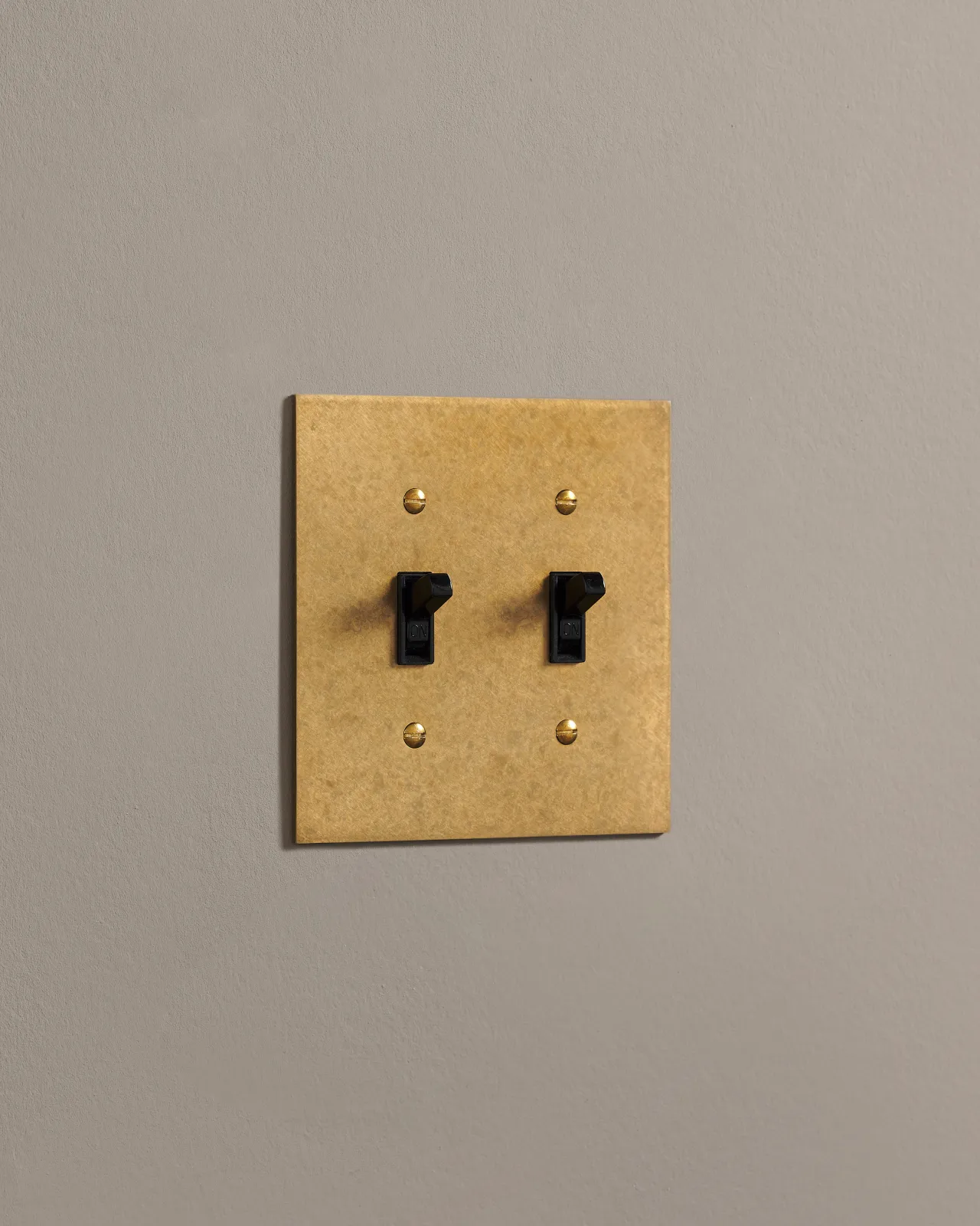 A side on shot on a toggle switch on an aged brass cover plate.