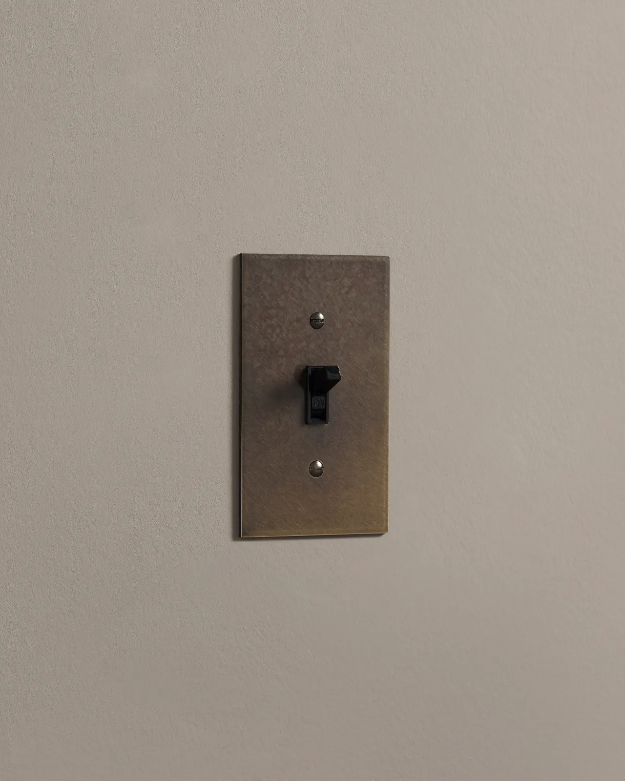 a side on shot of the toggle switch on an oxidised brass cover plate.
