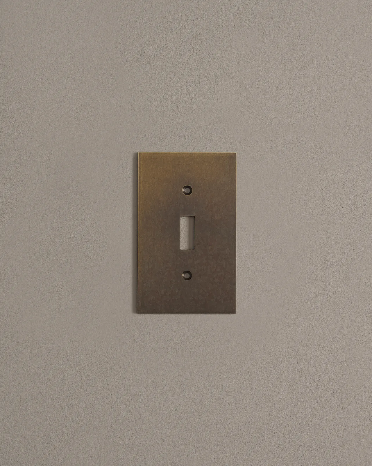 a front on shot of the toggle switch cover plate in oxidised brass finish.